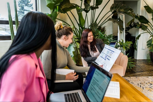 Three colleagues sitting on couch looking at a chart